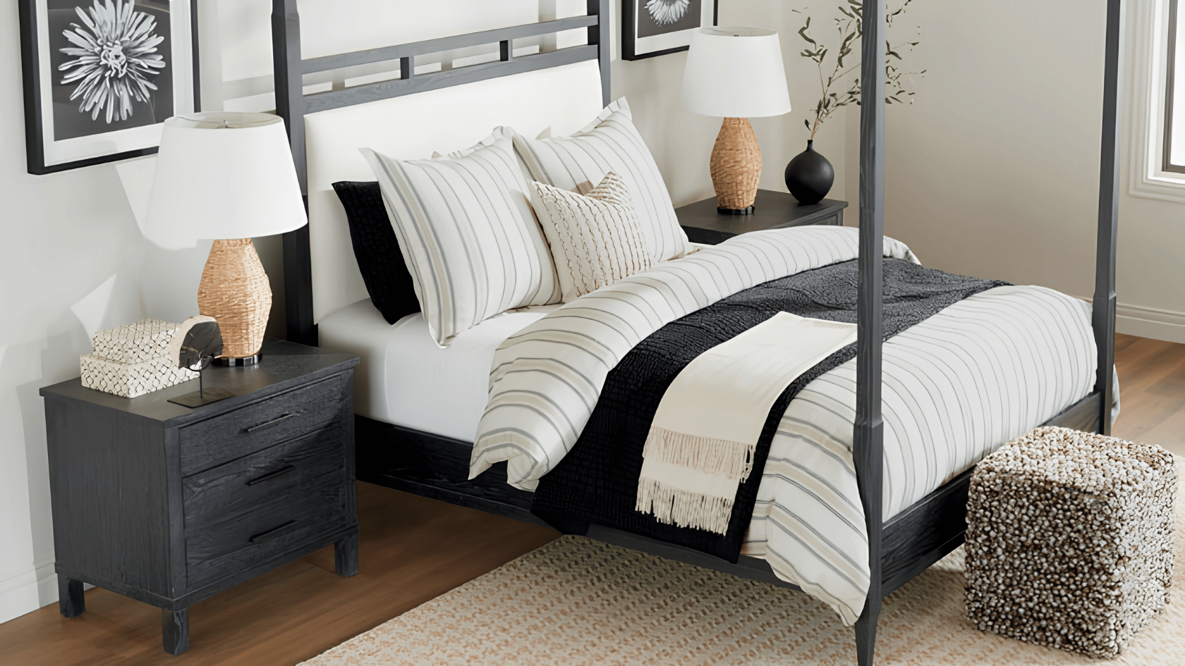 Black four-poster bed with striped white bedding and matching dark wood nightstands.