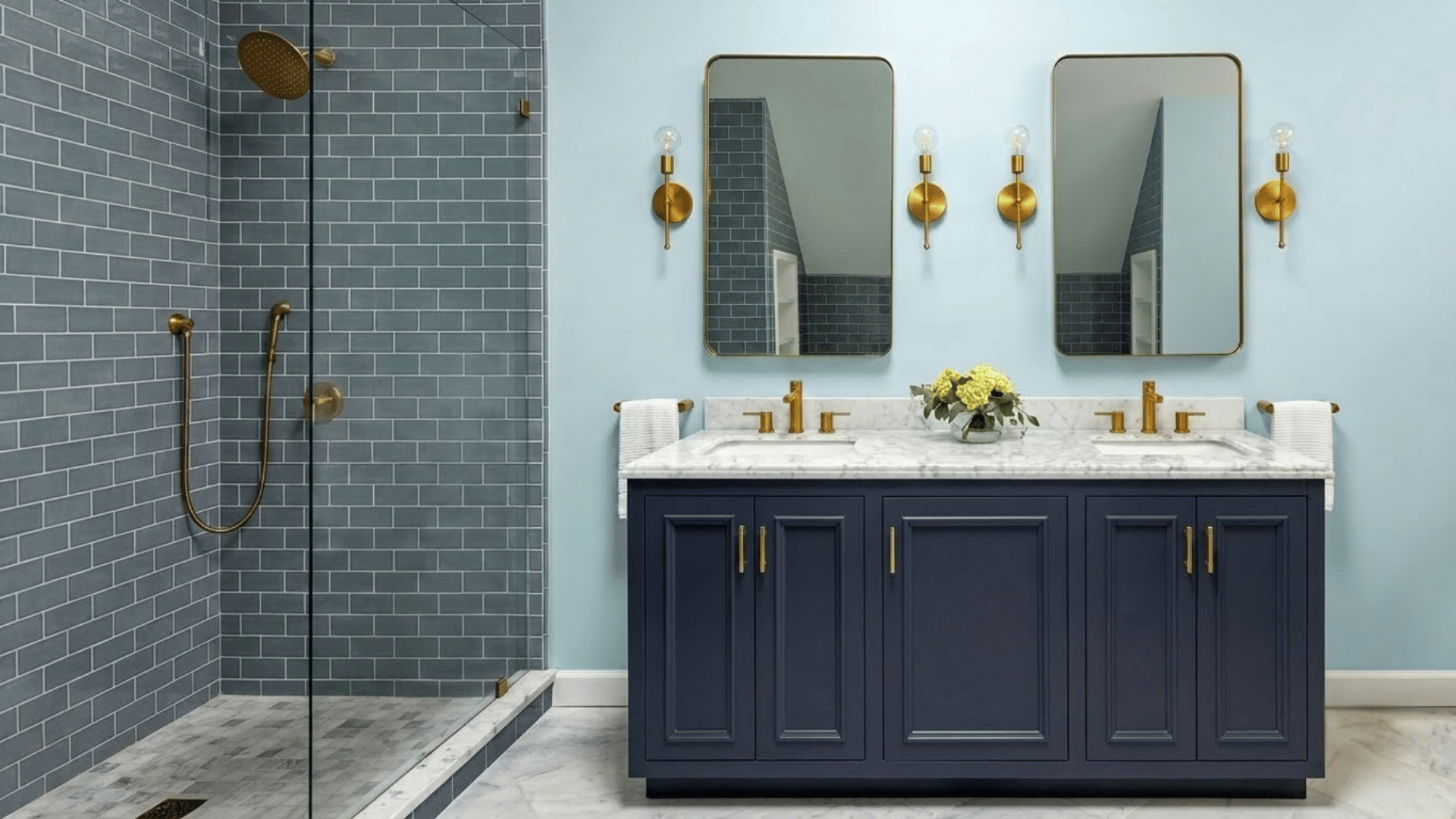 Blue bathroom ideas with navy vanity, gray tile shower, mirrors and gold fixtures