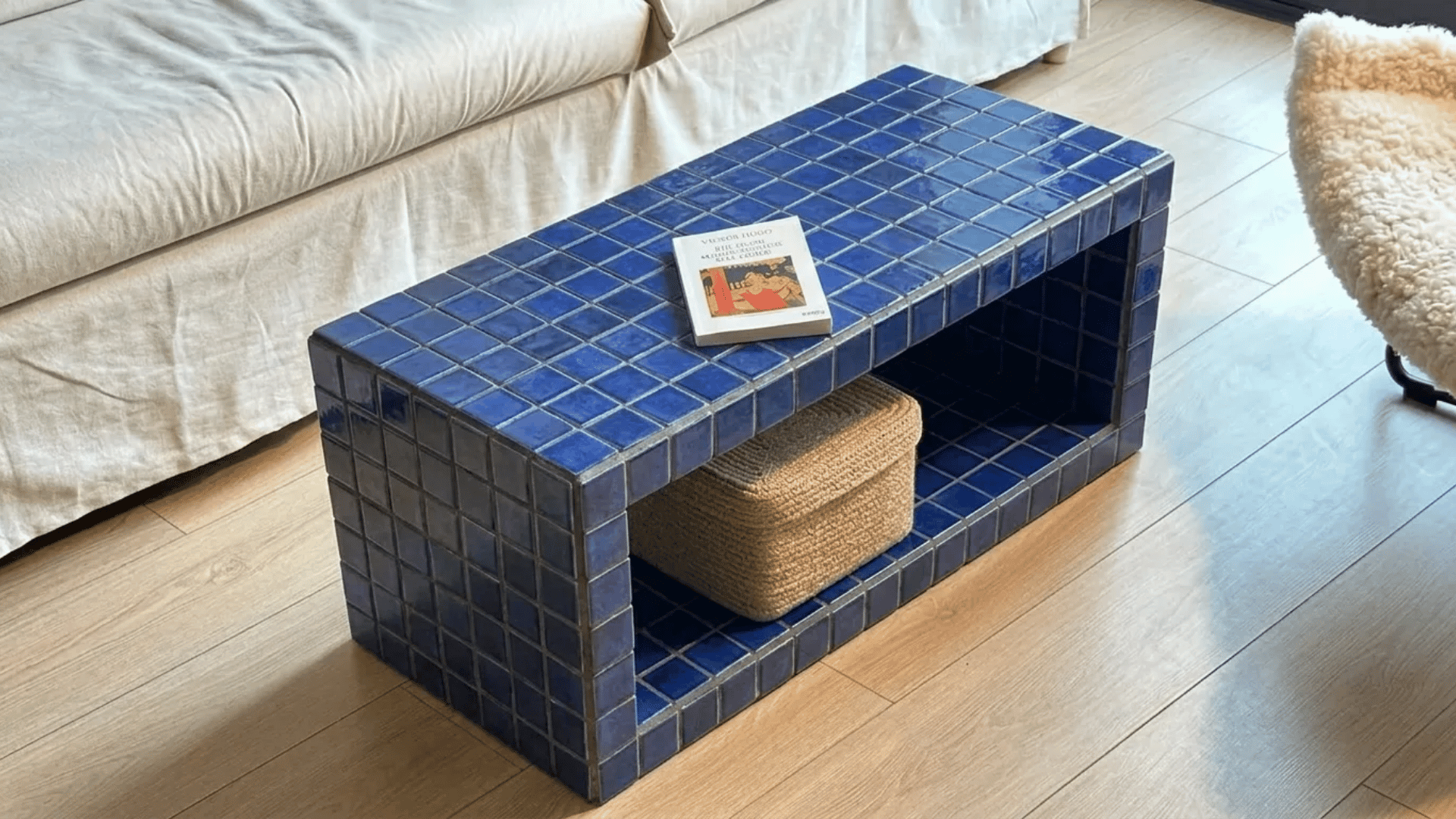Blue tiled storage coffee table with open shelf and woven basket underneath.
