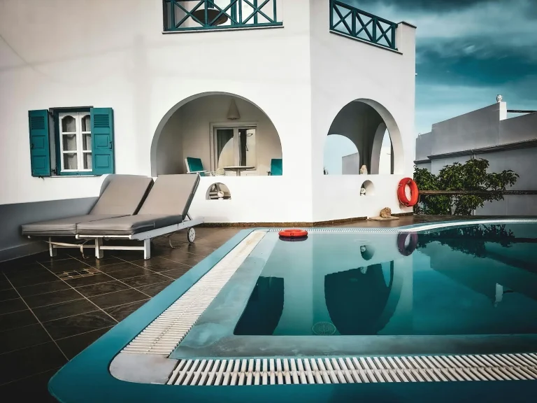 Outdoor poolside with sun loungers and arched building in a Mediterranean setting