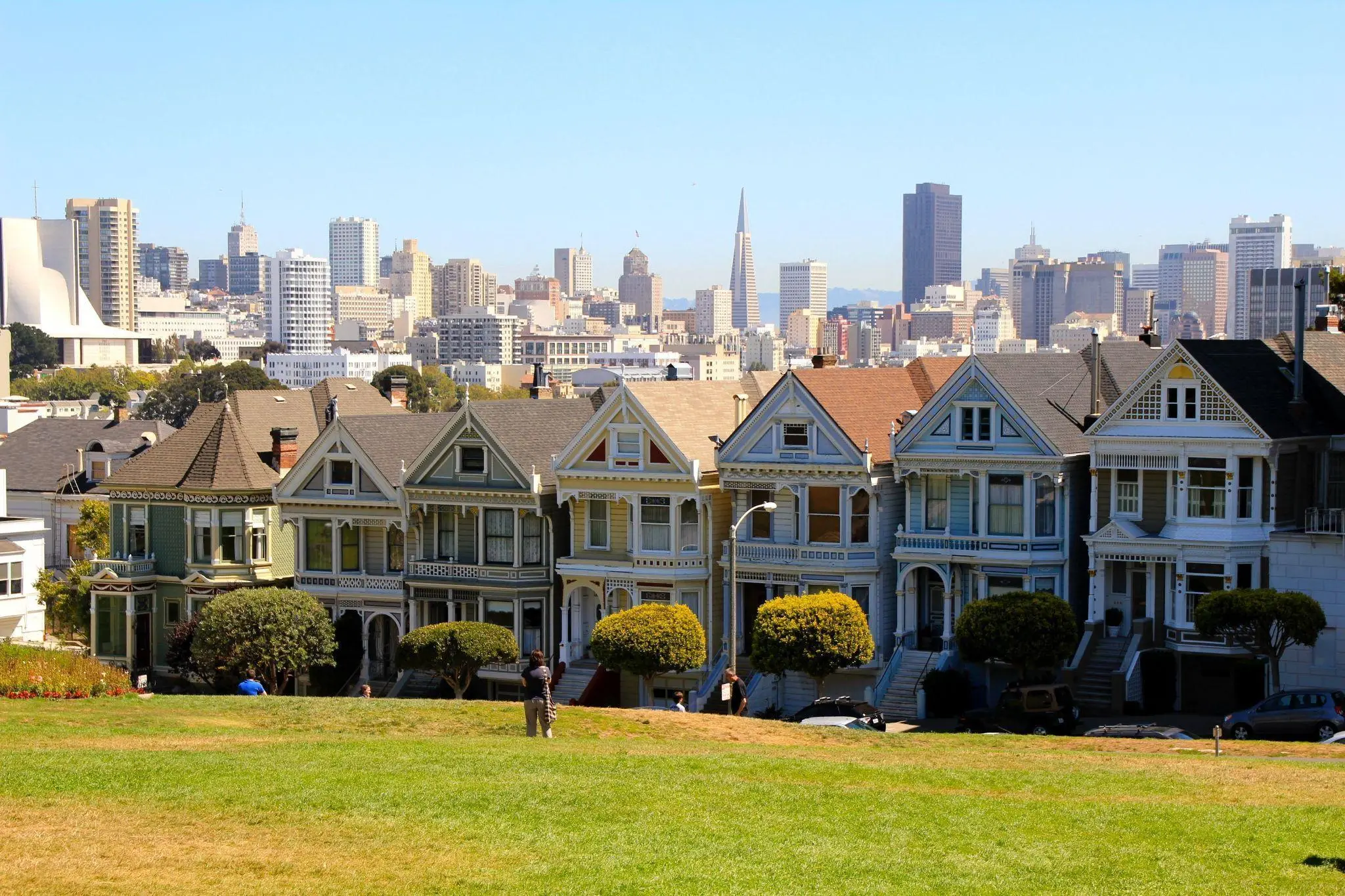 Victorian houses with San Francisco skyline in the background under clear blue sky