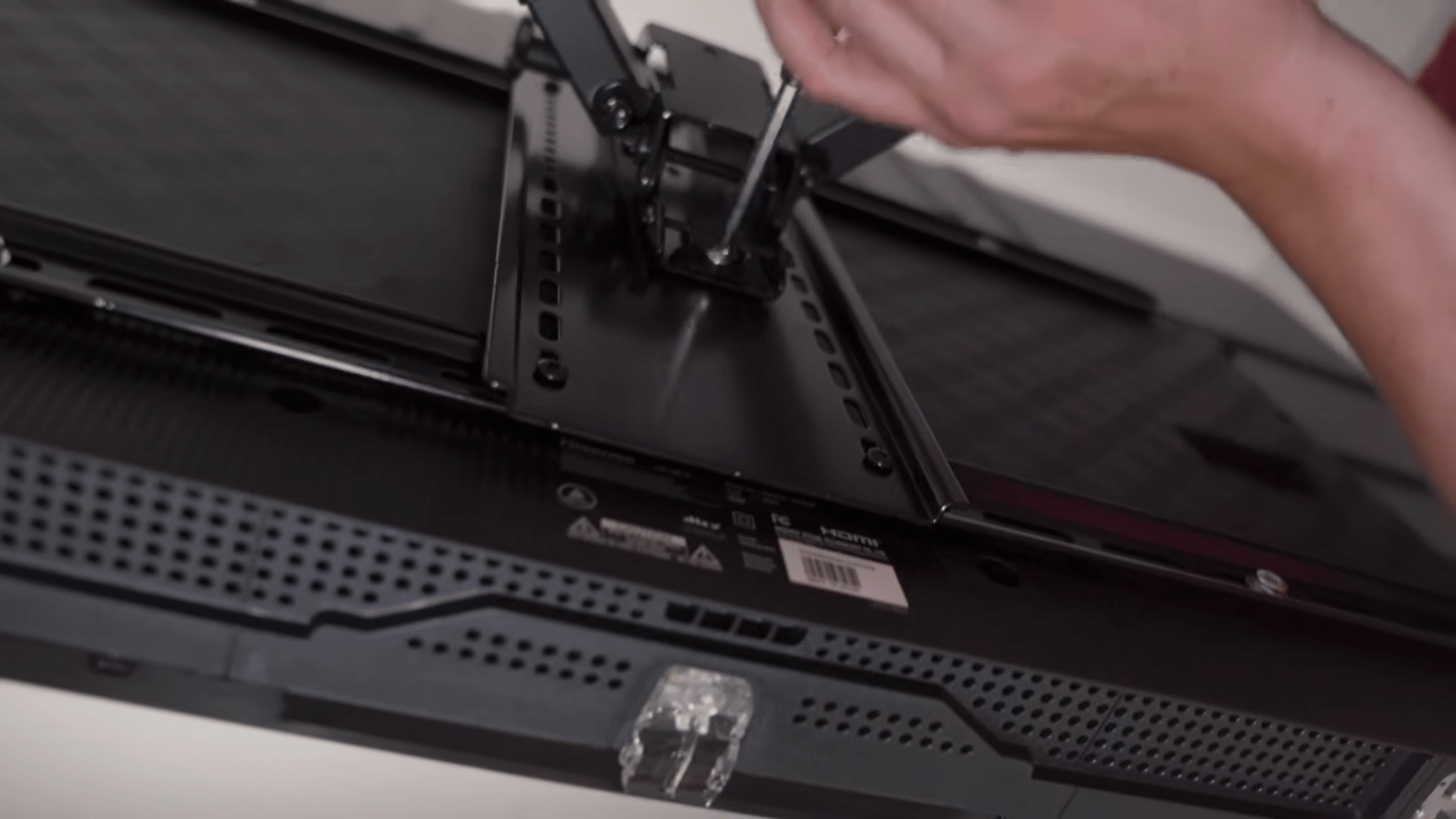 Connecting cables to a wall mounted TV during the final installation process.