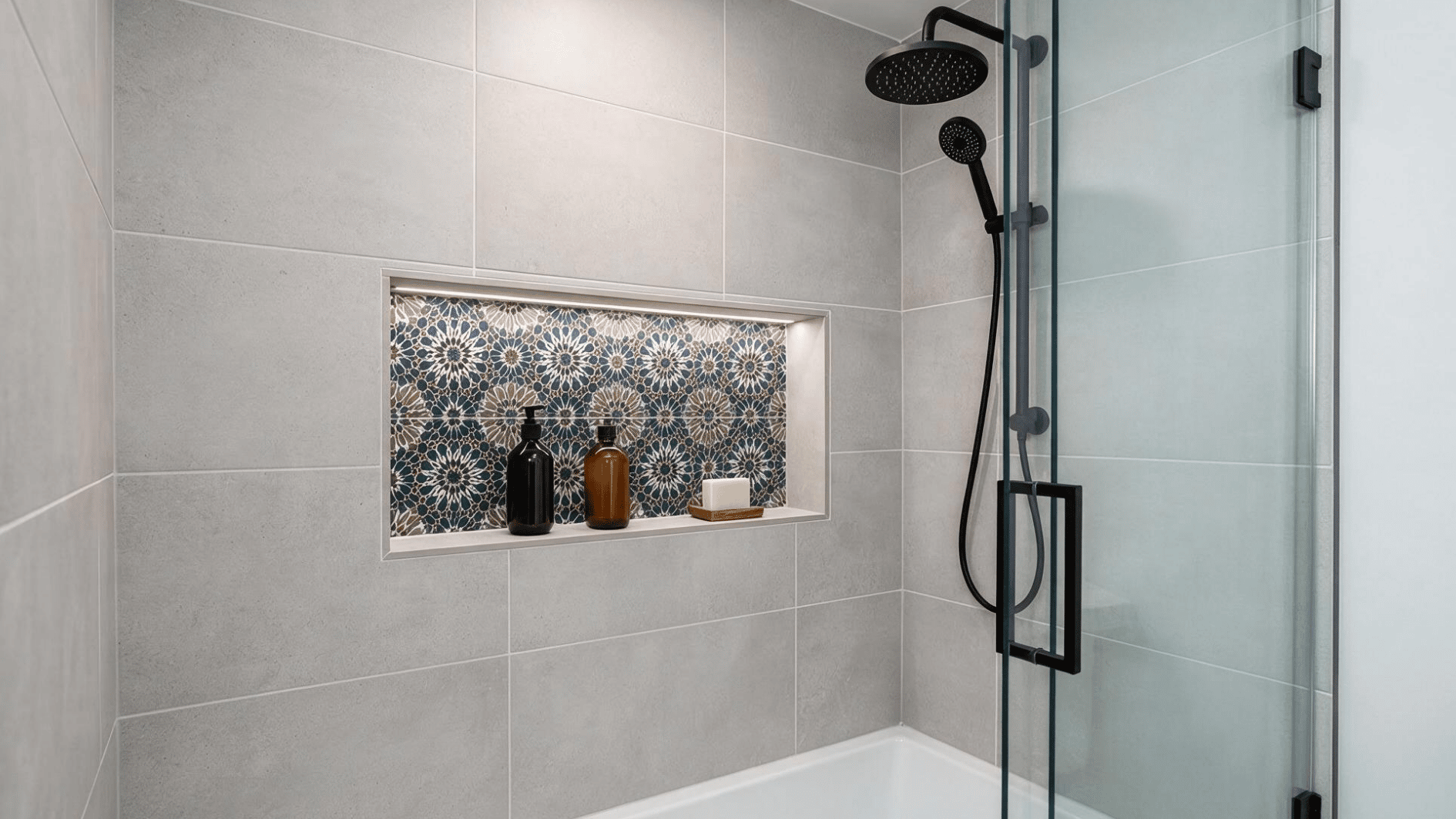 contrasting mosaic tile interior in a recessed shower niche with unbranded toiletries and modern bathroom design