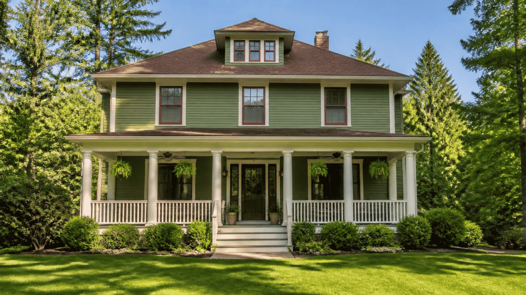 Craftsman style home with a wide front porch, tapered columns, green siding, and a landscaped yard.