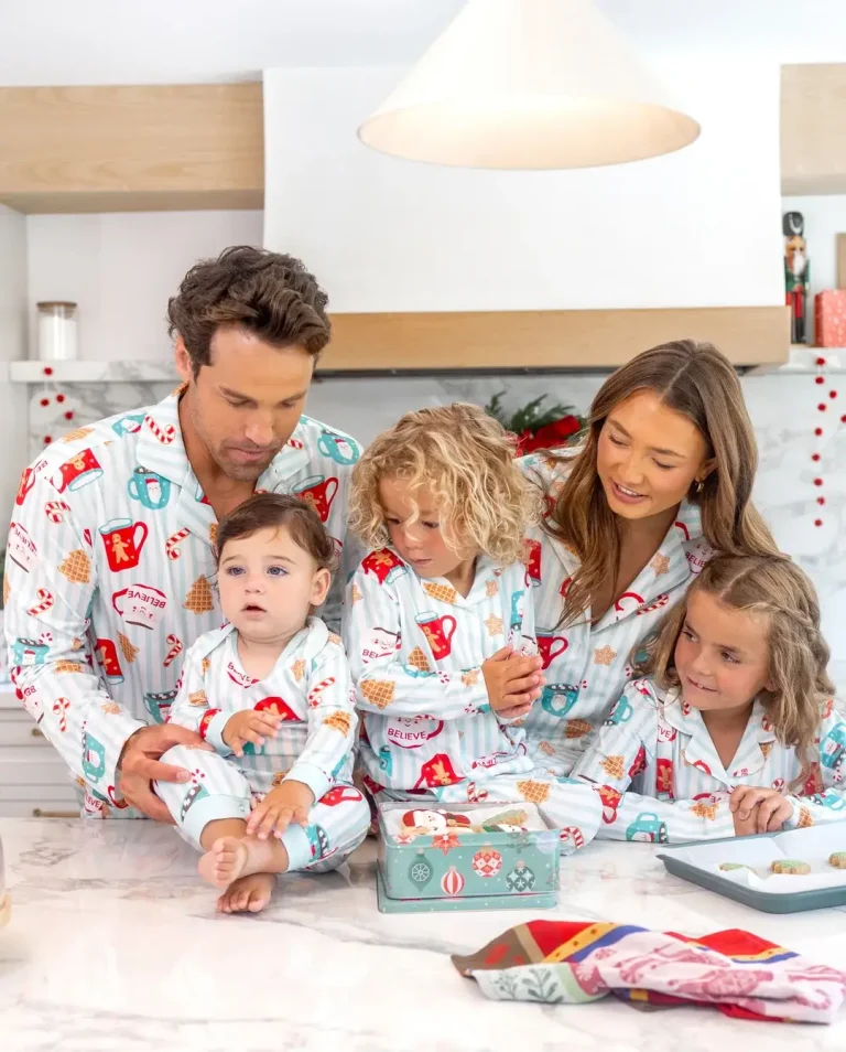 Family in matching holiday pajamas gathered at kitchen counter with cookie tins