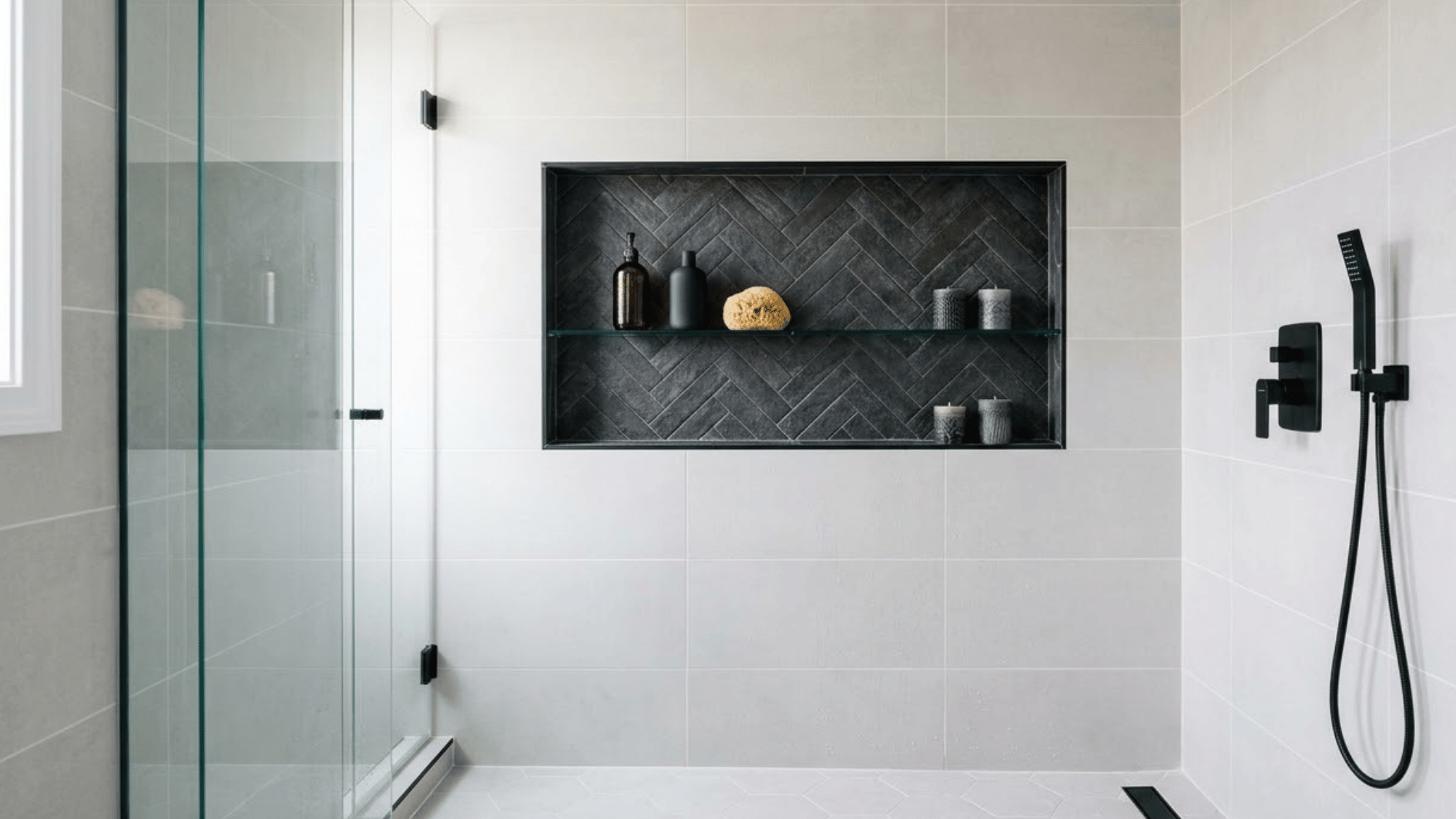 dark tile shower niche with toiletries and candles inside a modern tiled shower wall