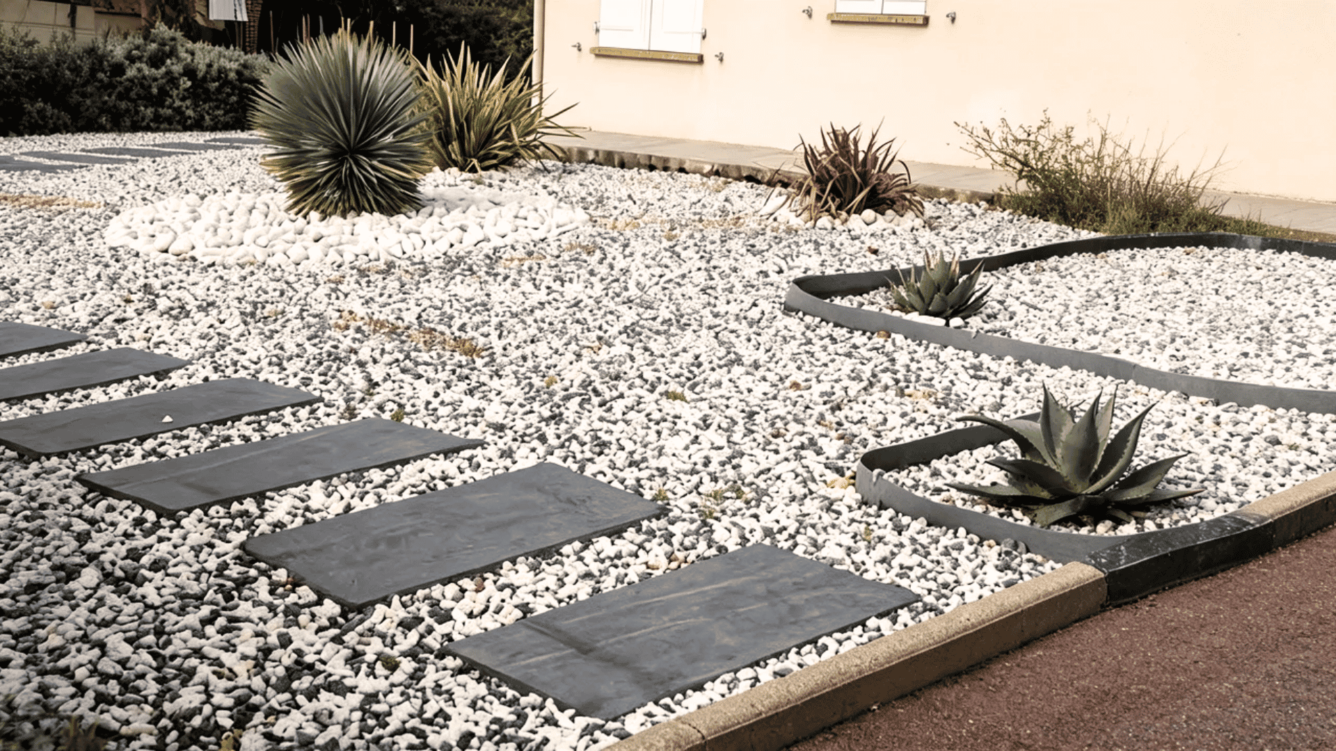 Flat stone slabs placed through gravel creating a modern walkway with planted edges.