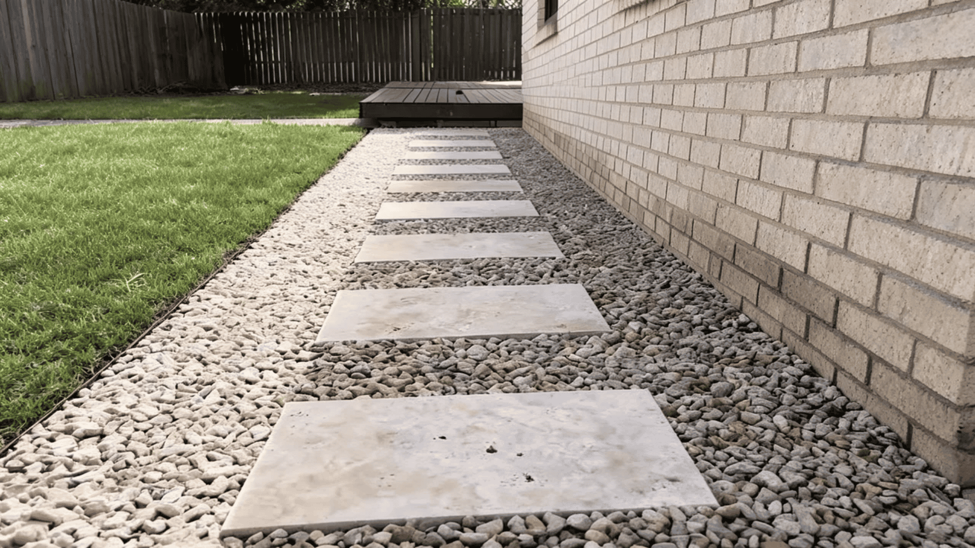 Gravel walkway with flat stepping stones leading through a backyard garden.