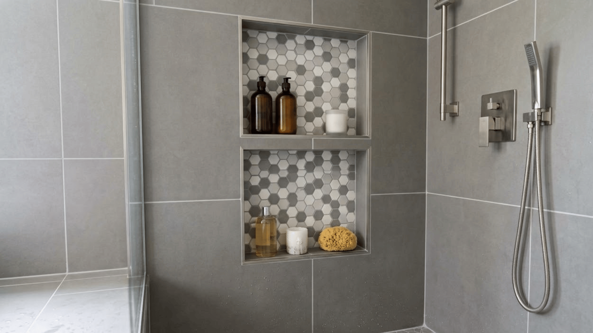 hexagon tile shower niche with toiletries and candles inside a modern tiled shower wall