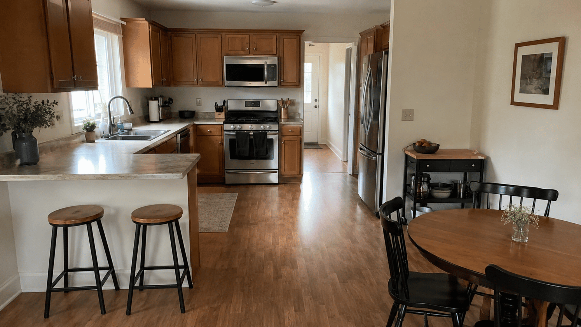 kitchen with peninsula bar stools, stove, fridge, movable cart, and round dining table