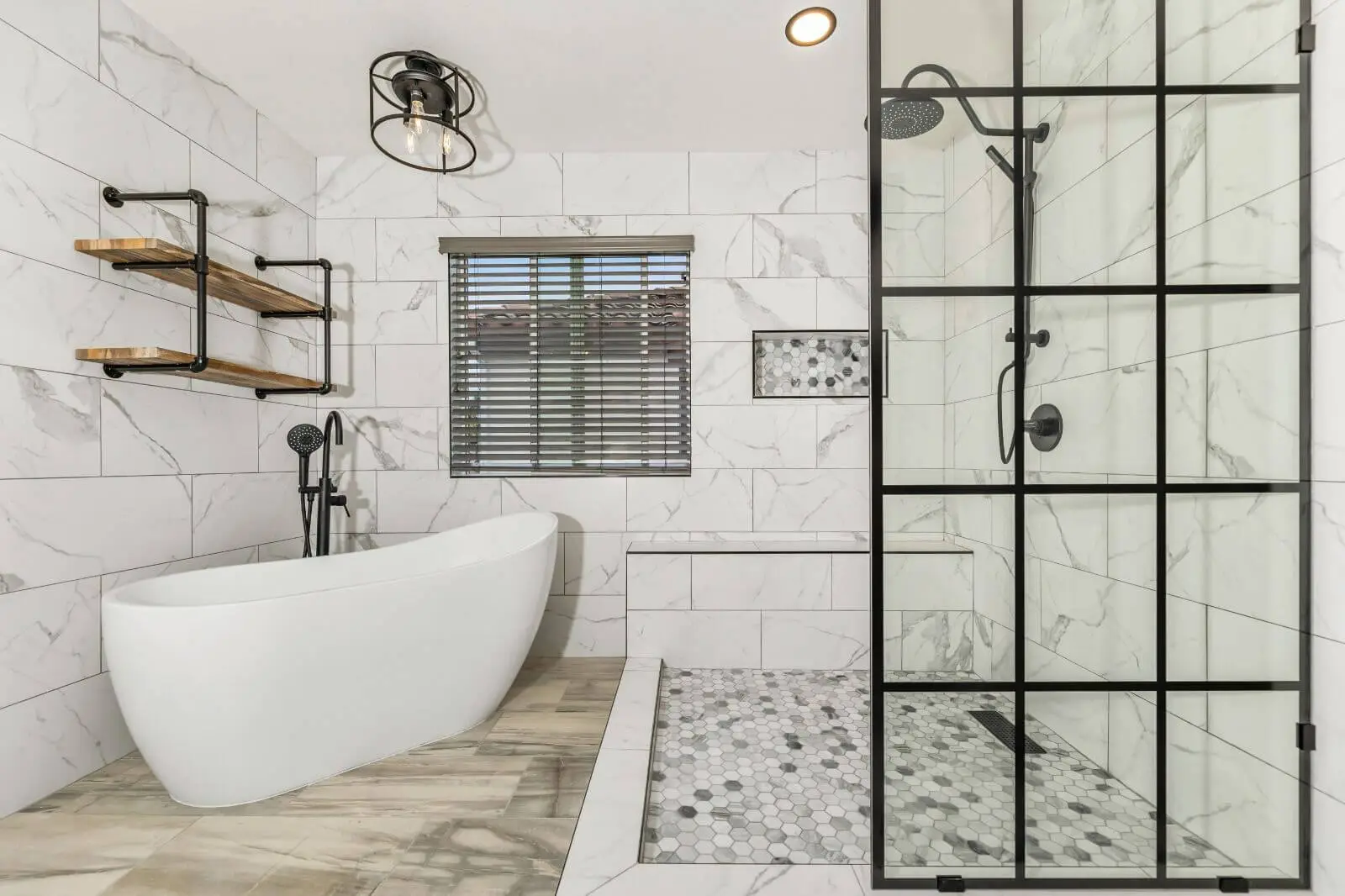 Modern bathroom with white freestanding tub, black framed shower, and marble tile walls