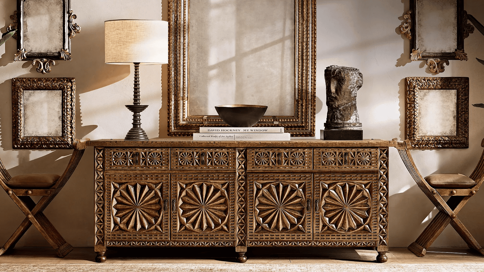 Ornate vintage console table with gold frames, sculptural decor, plants, and warm classic interior styling.
