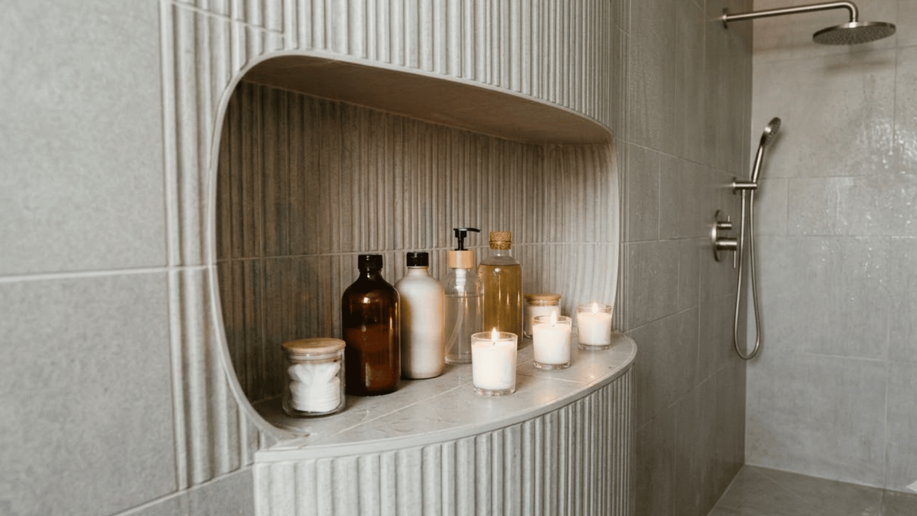 outward curve shower niche with toiletries and candles inside a modern open tiled shower wall
