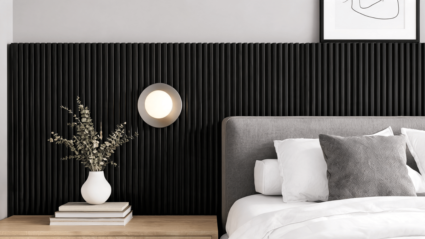 Black ribbed wall panels behind a bed with bedside table, vase, lamp, pillows, and framed wall artwork.