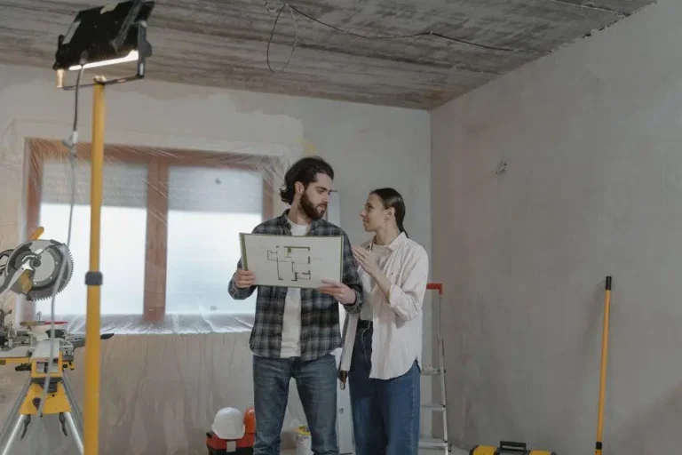 Couple discussing floor plan in unfinished room with construction tools around