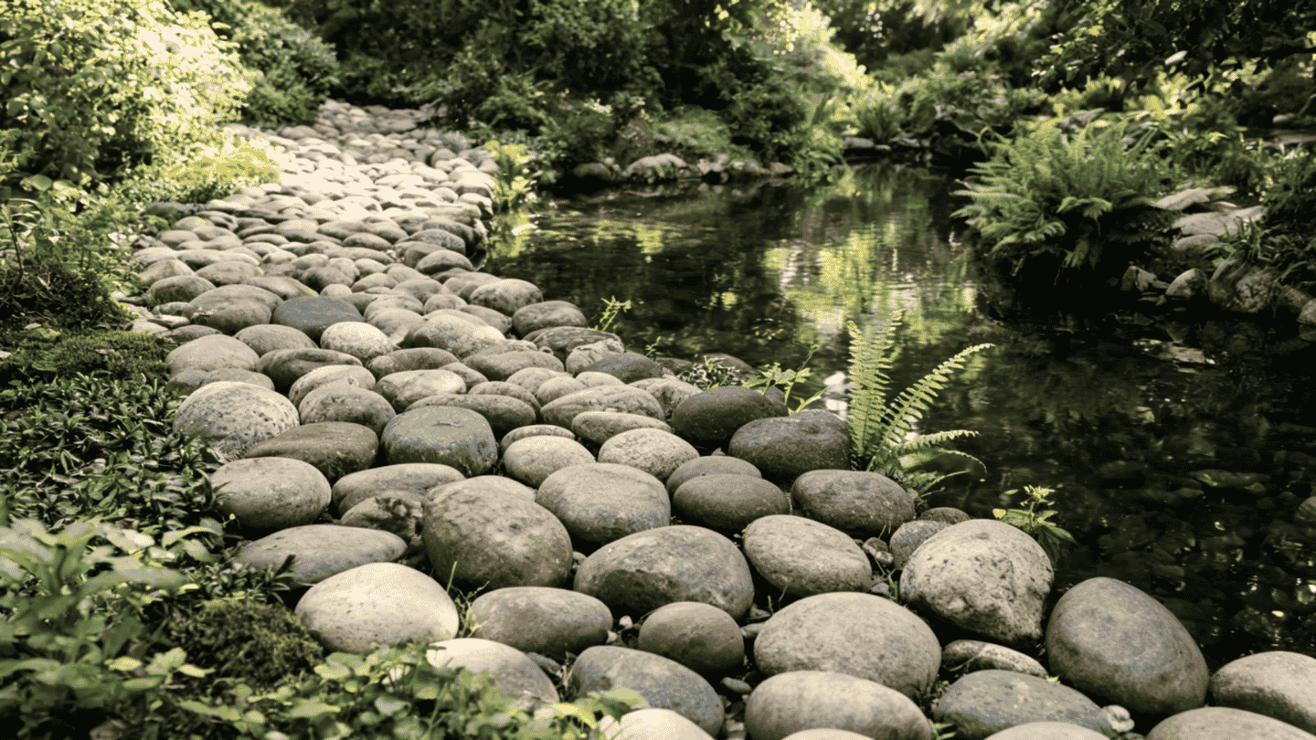 Smooth rounded river stones walkway ideas beside plants and a water feature.