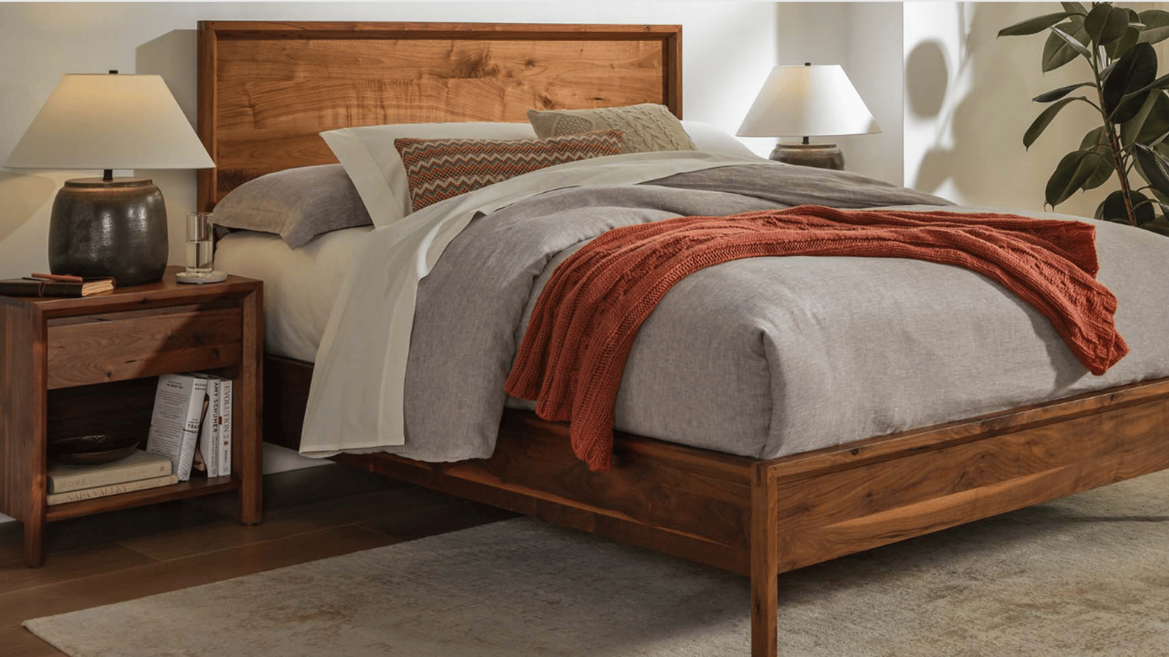 Warm neutral bedroom with wooden furniture, layered bedding, and cozy modern decor.