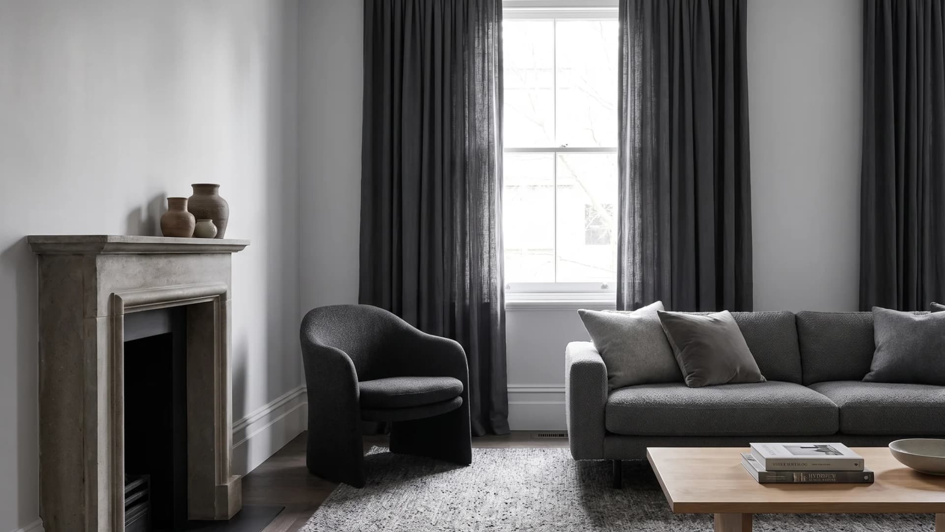 Charcoal gray living room decorated with a plush velvet sofa, bouclé accents, and a pale gray rug.