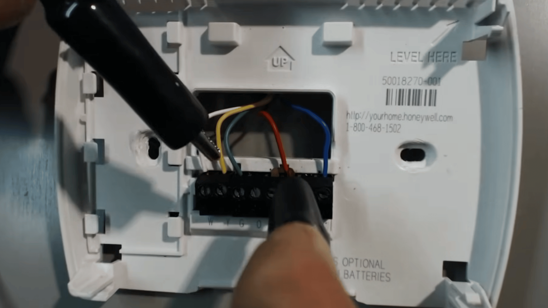 screwdriver loosening thermostat terminal screws before removing wires for a direct HVAC system test