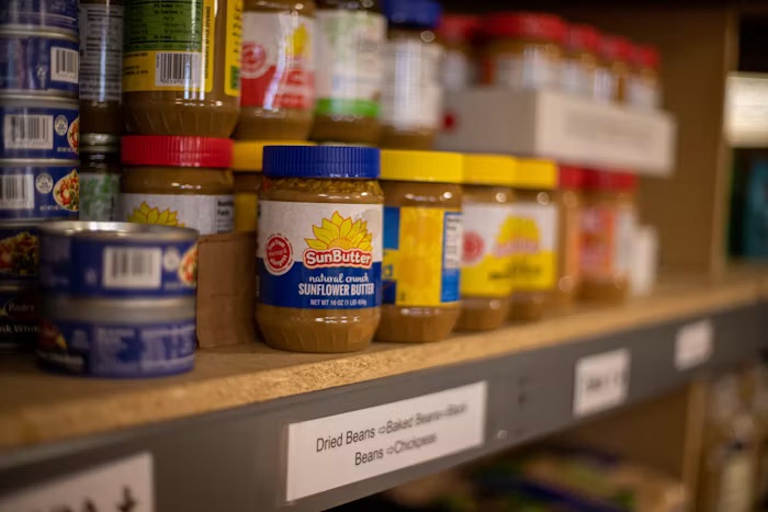 Jars of sunflower butter with colorful lids on pantry shelf in warm lighting