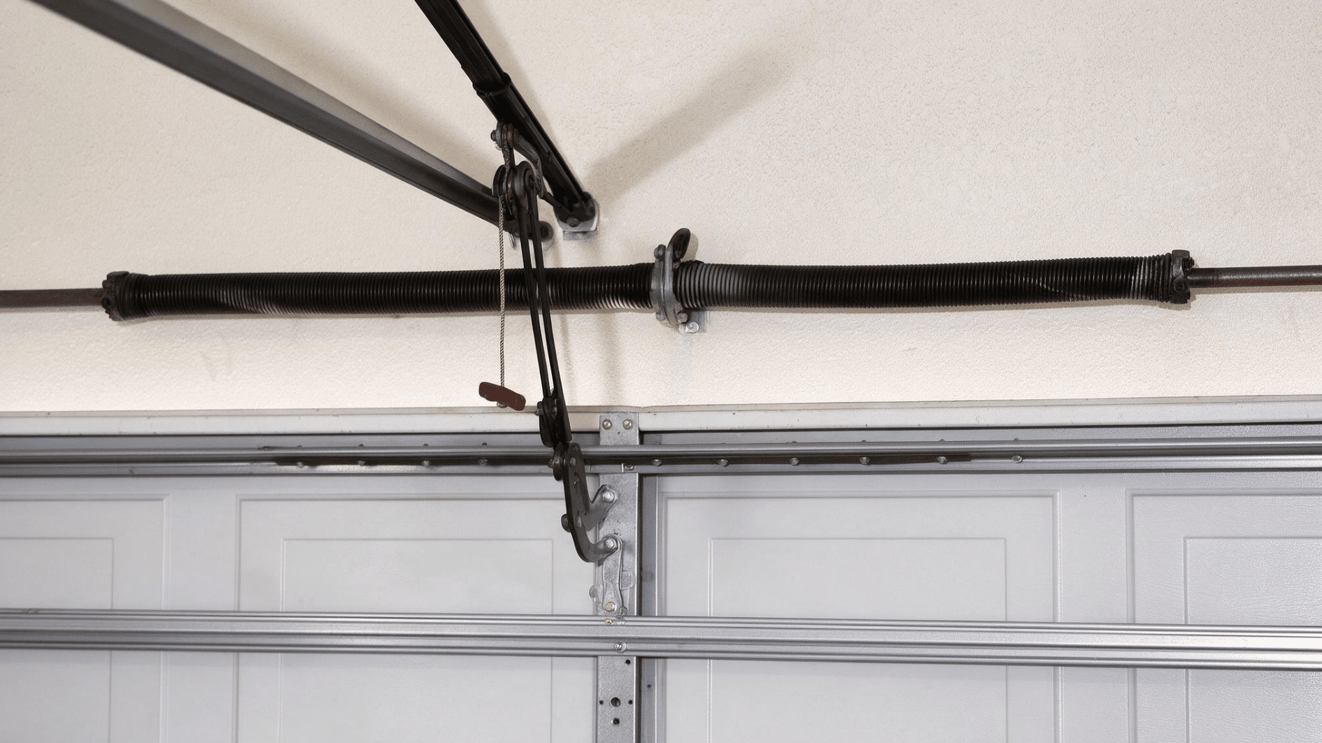 garage door high-cycle spring system mounted above a sectional door with tracks and lifting hardware visible