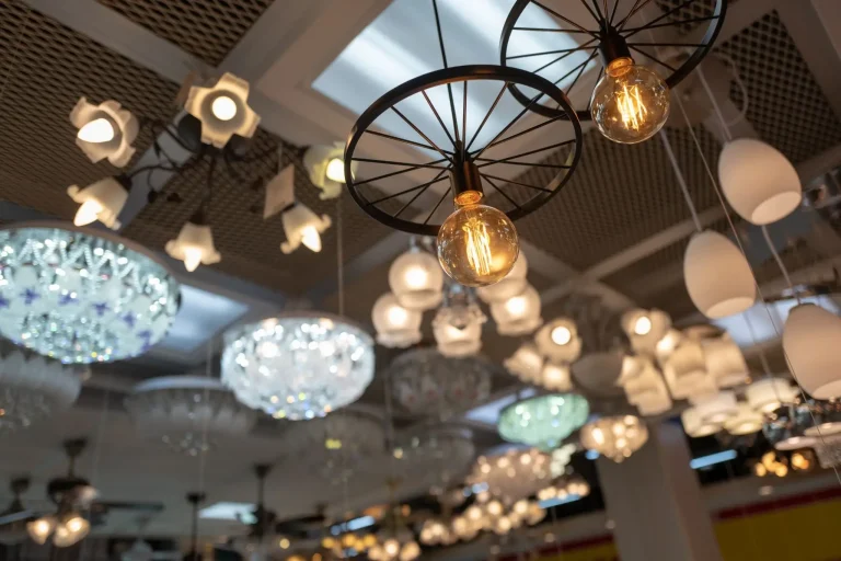 Ceiling display of various modern light fixtures in a showroom under warm lighting
