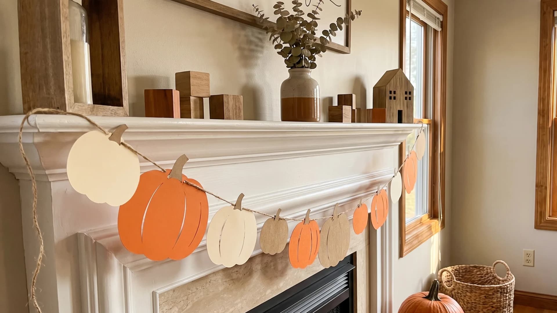 A handmade paper pumpkin garland made from orange and cream cardstock strung along natural jute twine.