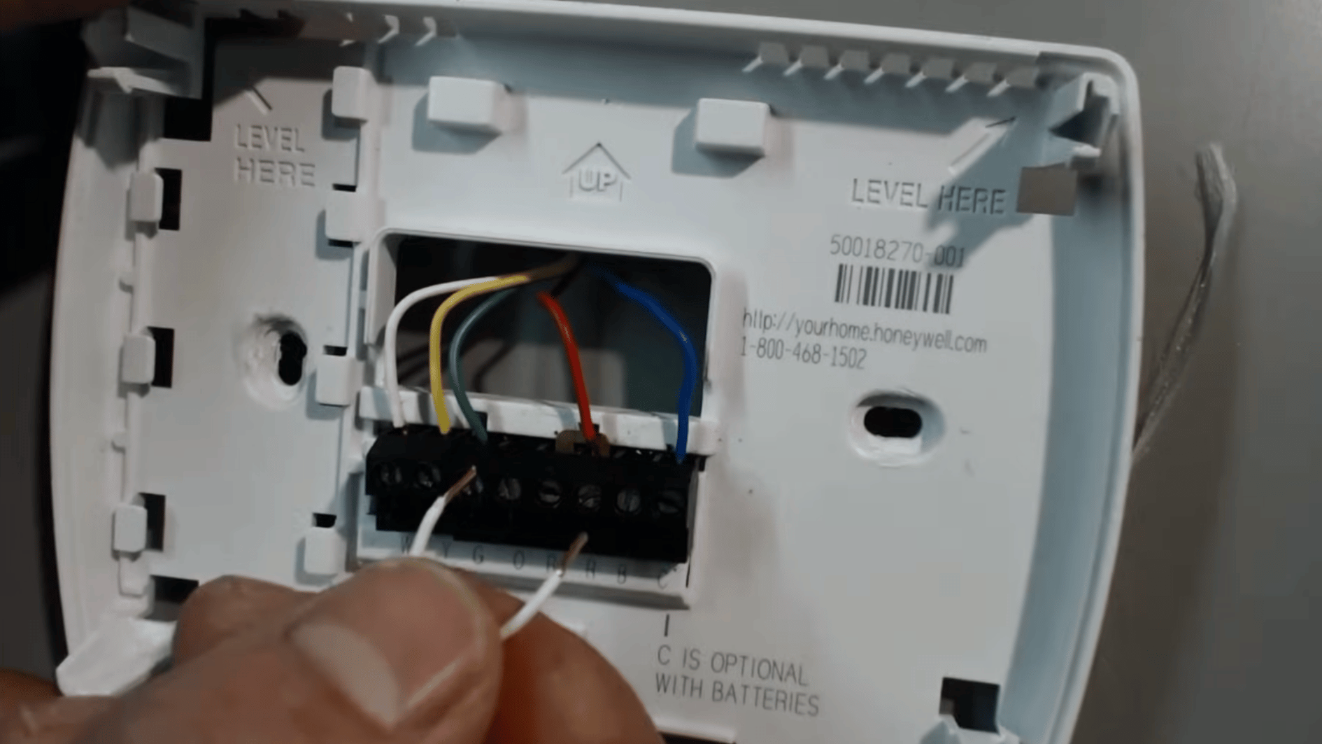 short jumper wire positioned near exposed thermostat terminals for testing the HVAC fan circuit