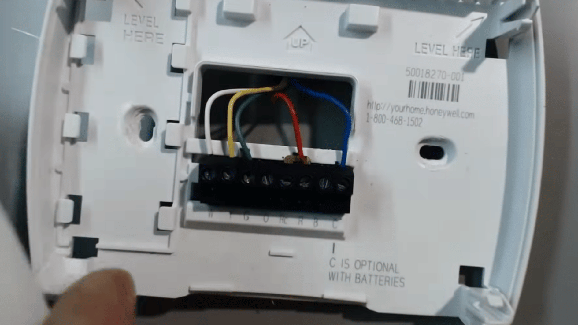 open thermostat base showing colored HVAC wires and terminal connections after removing the faceplate