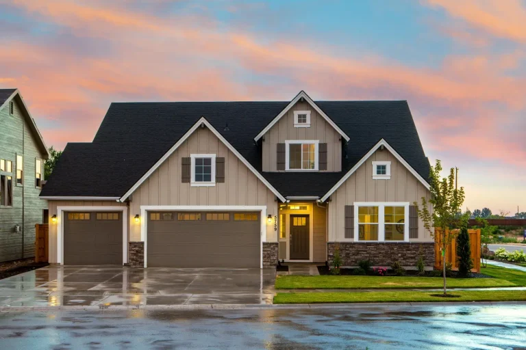 Two-story suburban home with three-car garage at sunset under a vibrant sky