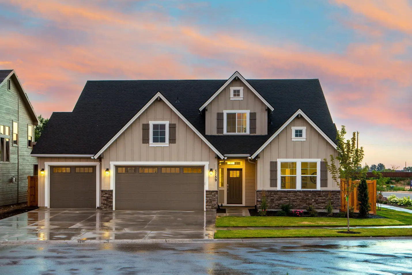Two-story suburban home with three-car garage at sunset under a vibrant sky